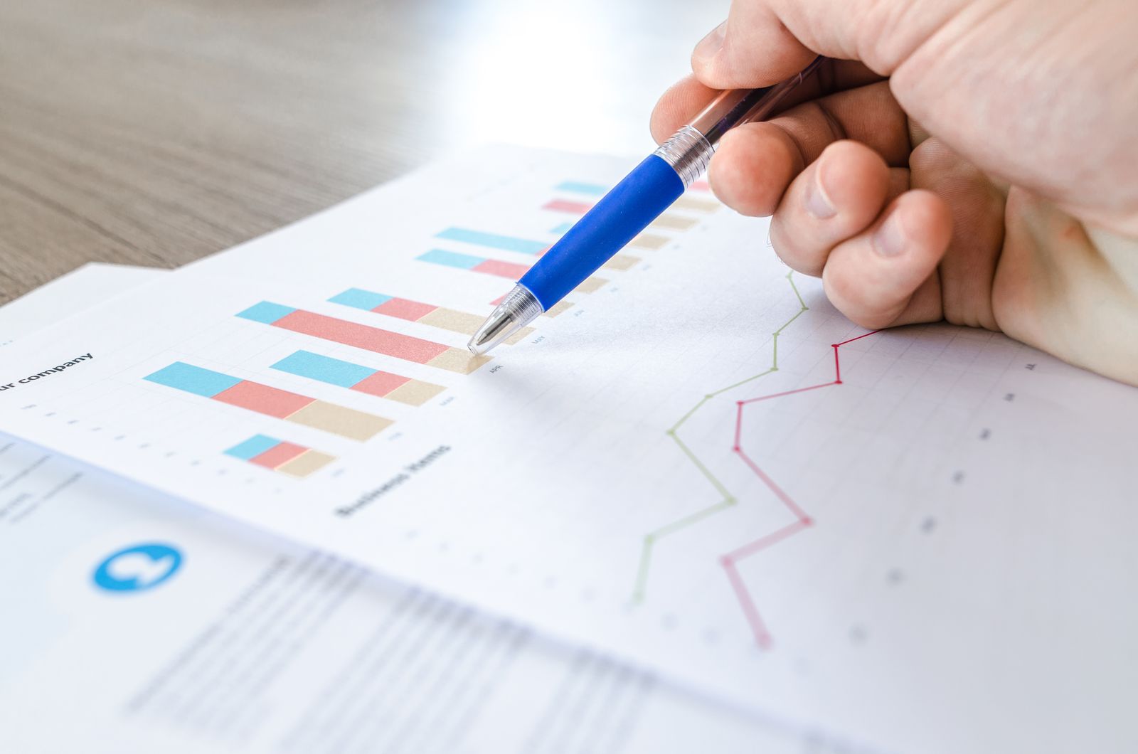 Mano con bolígrafo revisando gráficos impresos
